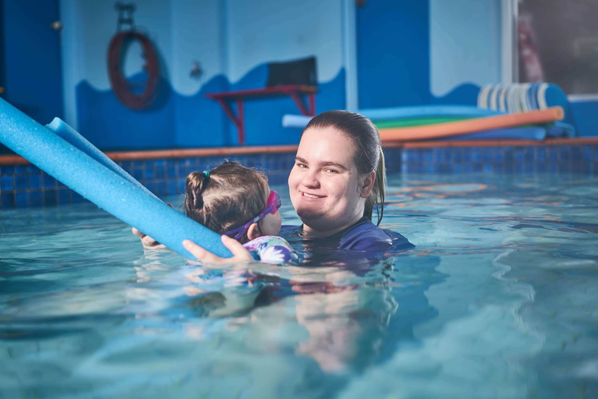 DES participant Maddy smiles in the pool as she teaches a child to swim