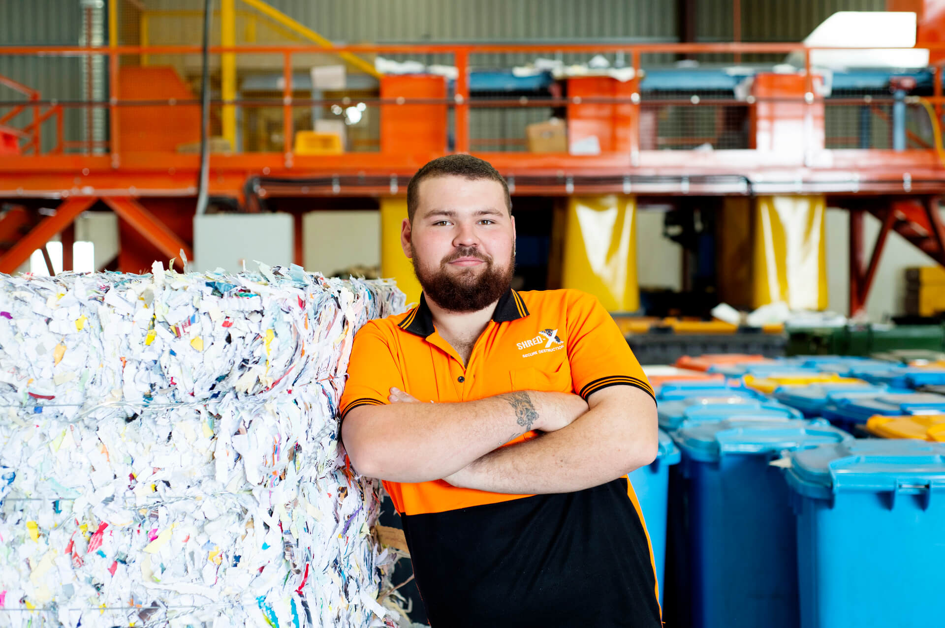 Jarryd smiles leaning against a stack of shredded paper. 