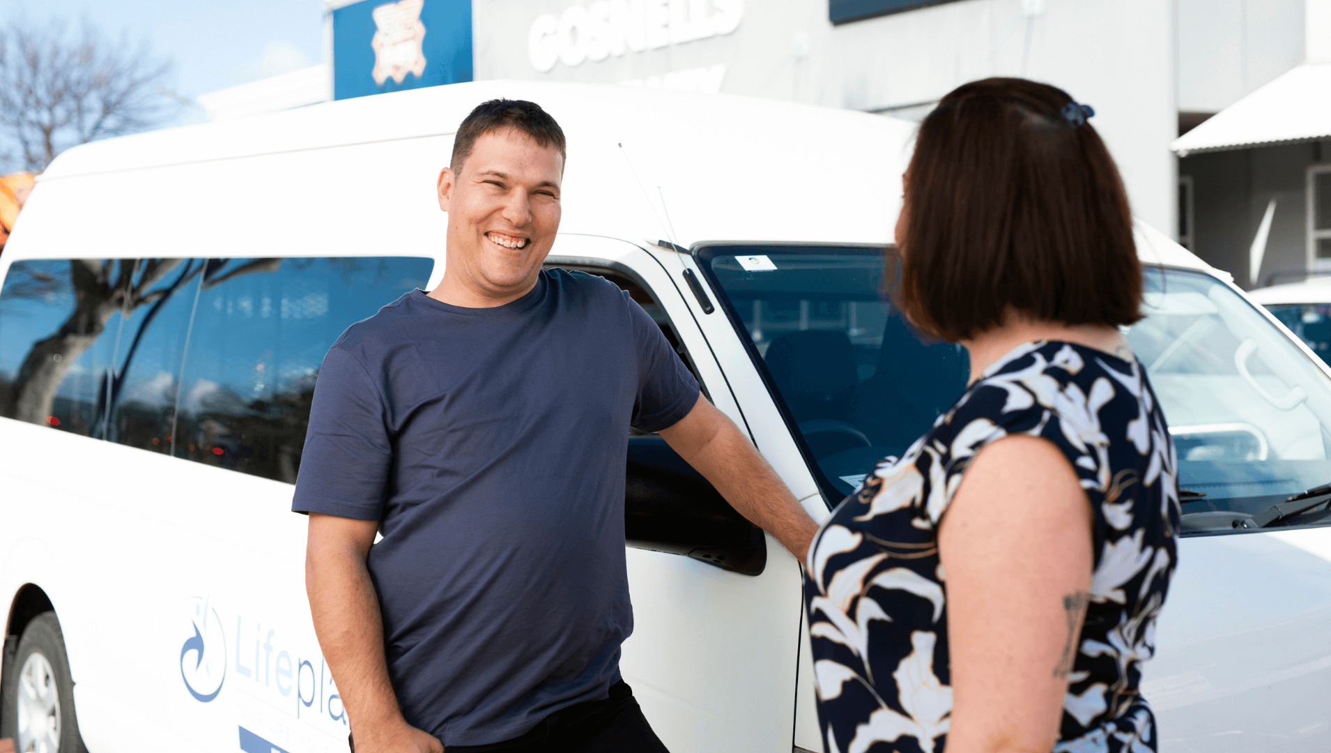 Alexander talking with a woman infront of a vehicle