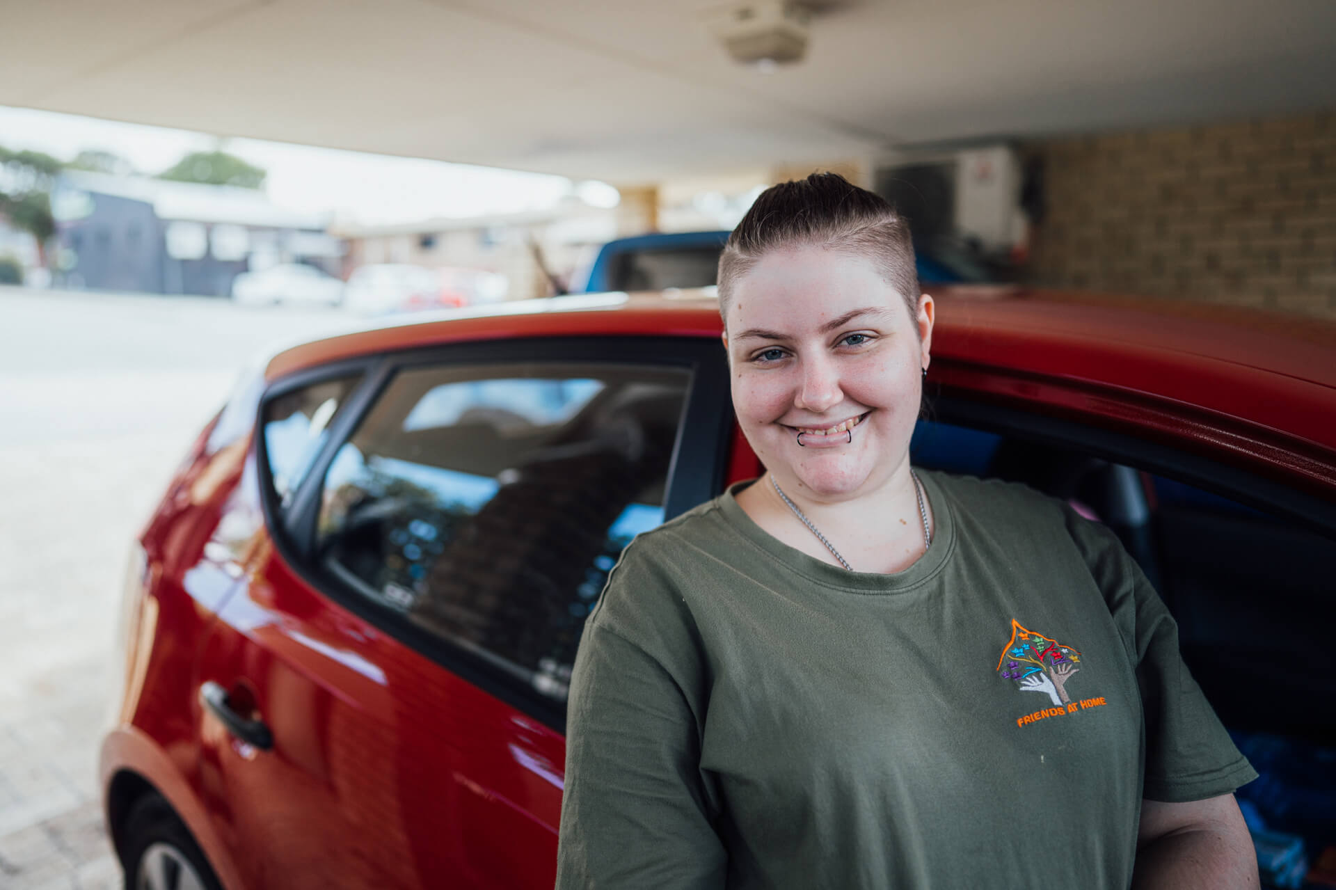 Young woman smiling next to a red car