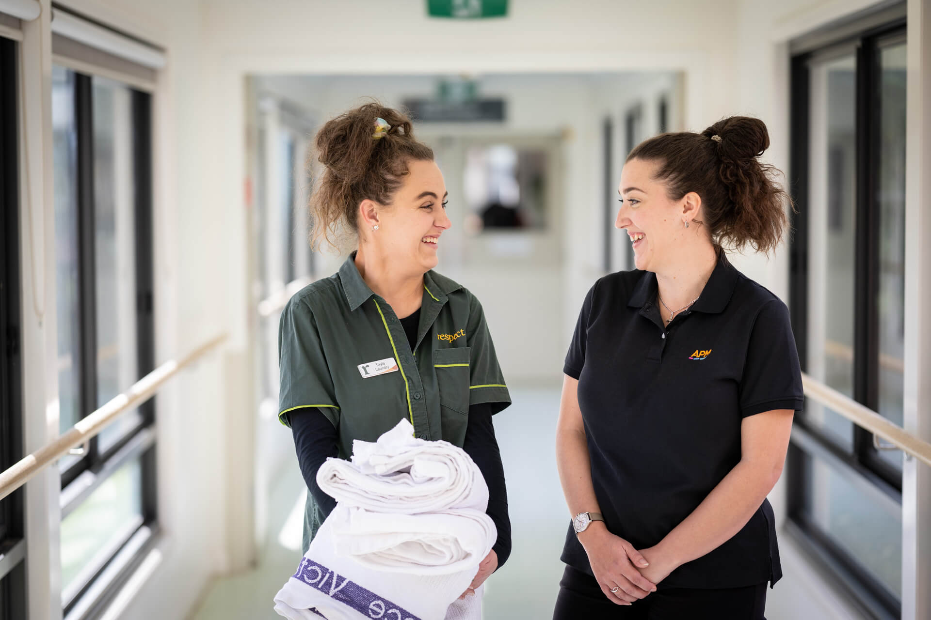 DES participant Tayla smiles with an APM consultant in a corridor