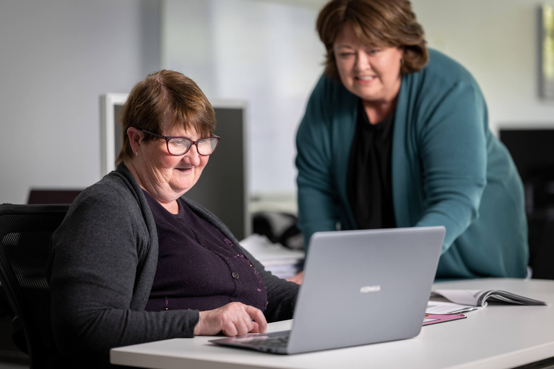 A DES participant sitting at a laptop in an APM office