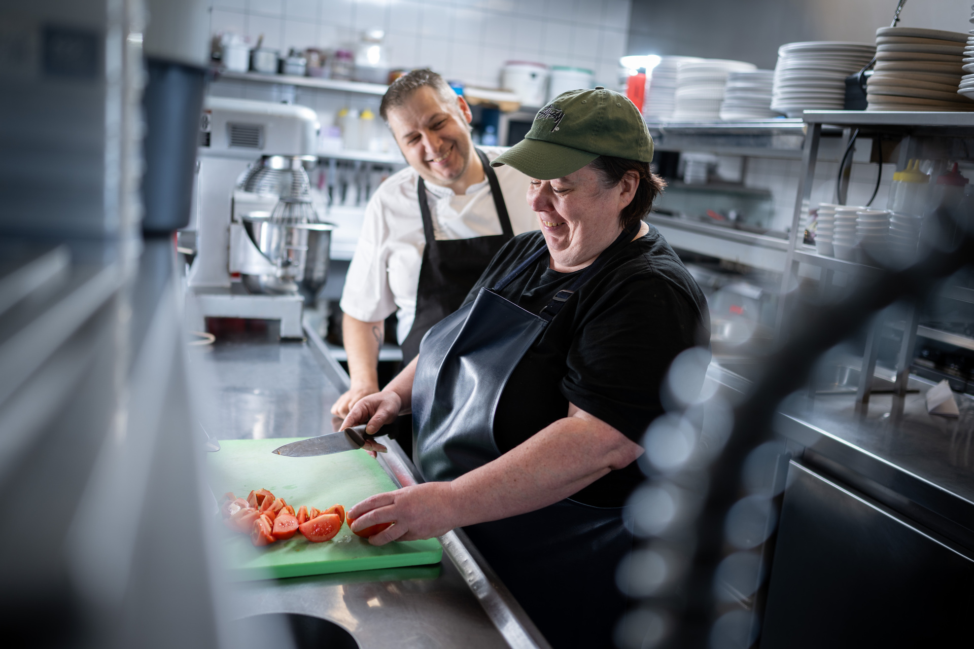 Two people working in a kitchen slicing food