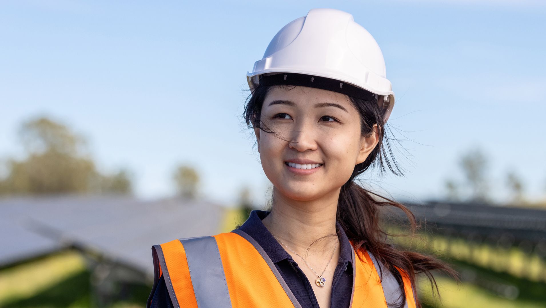 Young woman apprentice smiles in a field of solar panels