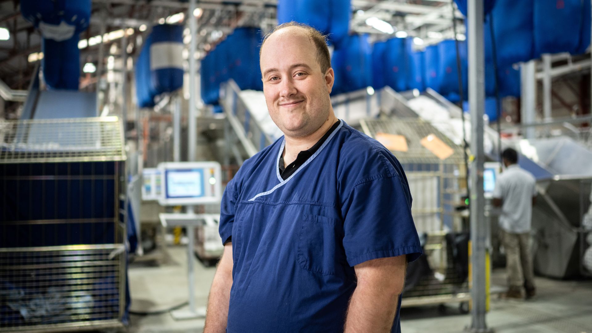 DES participant Stephen in a blue top standing inside a factory