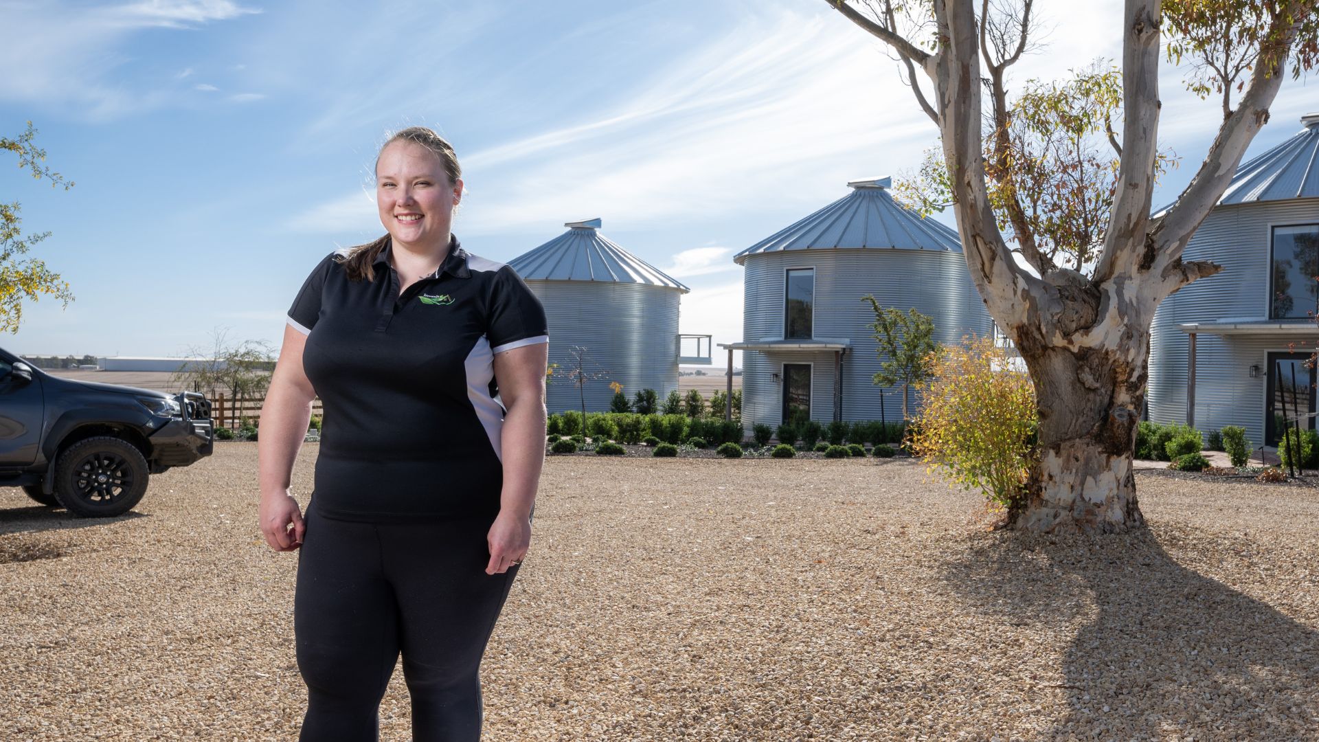 DES participant stands outside with blue sky and buildings in background