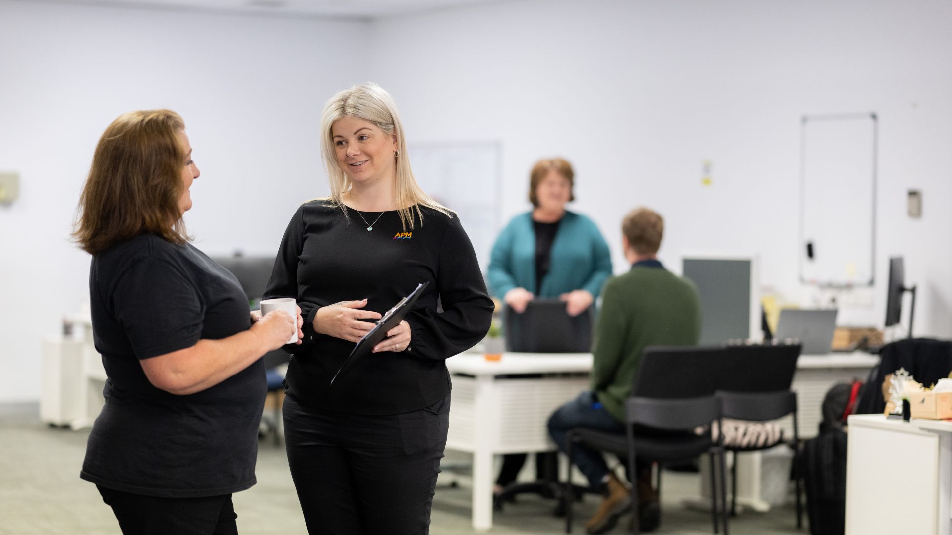 An APM employment consultant smiles in a black top inside an APM office