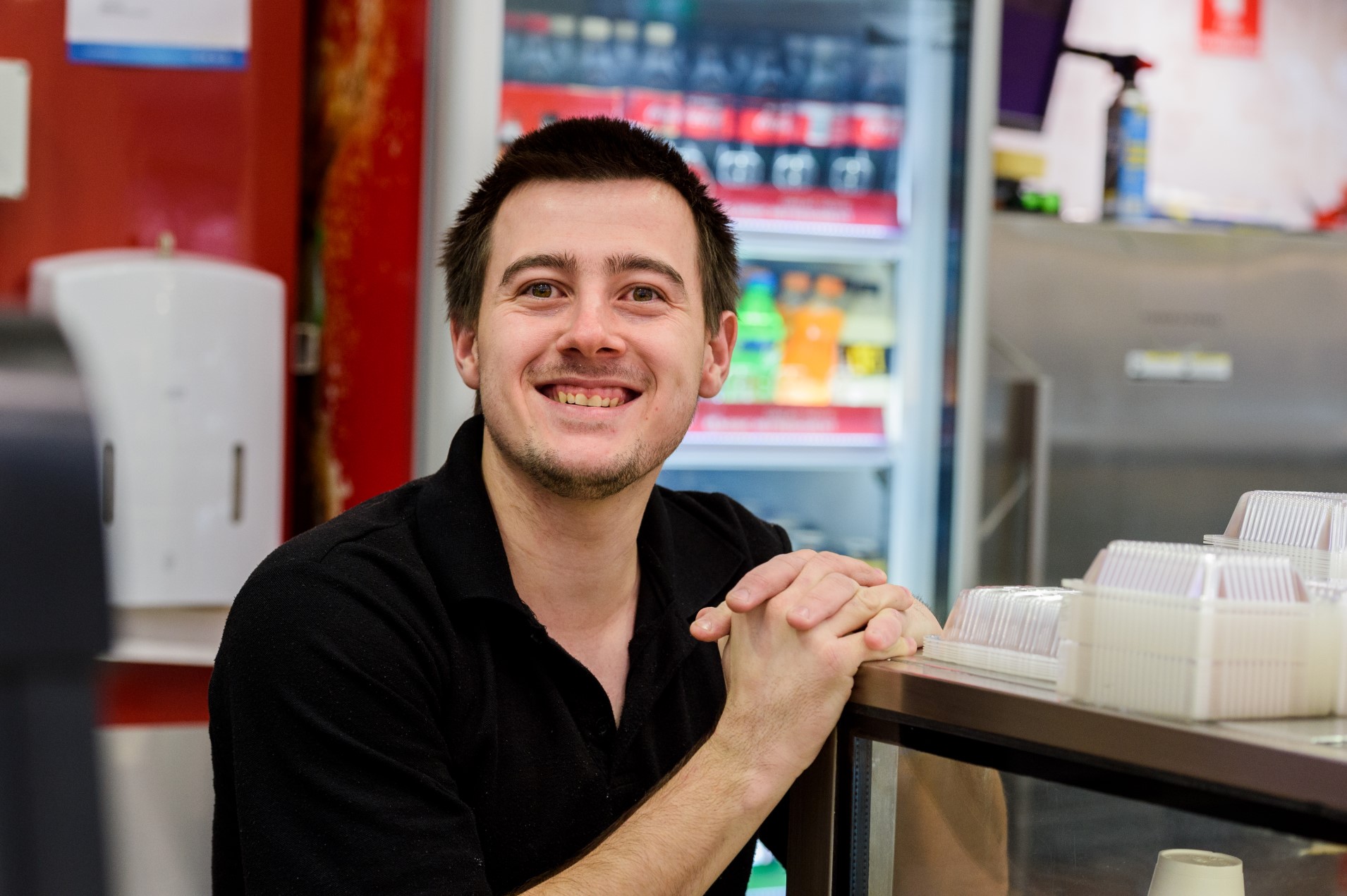 Dale smiles from the counter of his cafe workplace