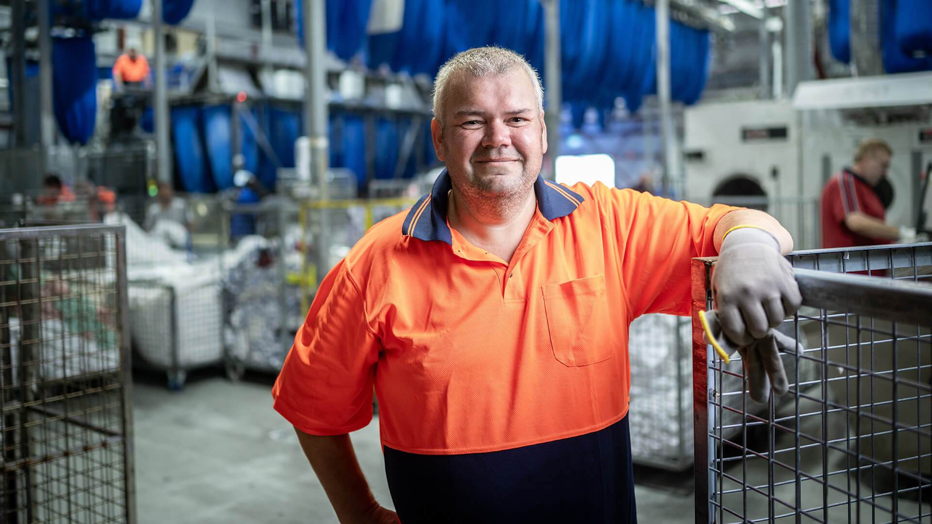 DES participant Geoff smiles in an orange top in a warehouse