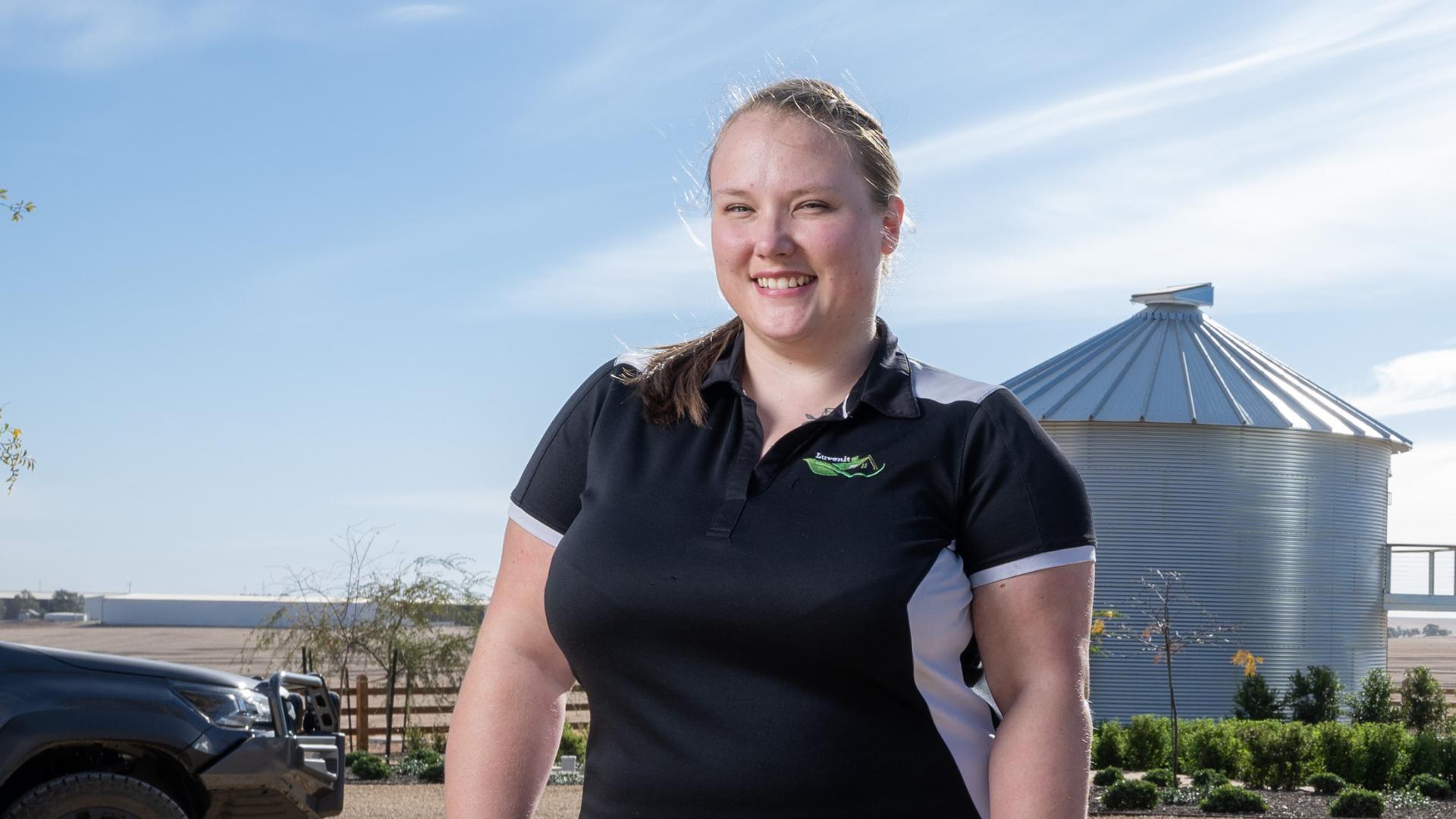 DES participant Ngaire smiles in work uniform outside a rural property in the sunshine