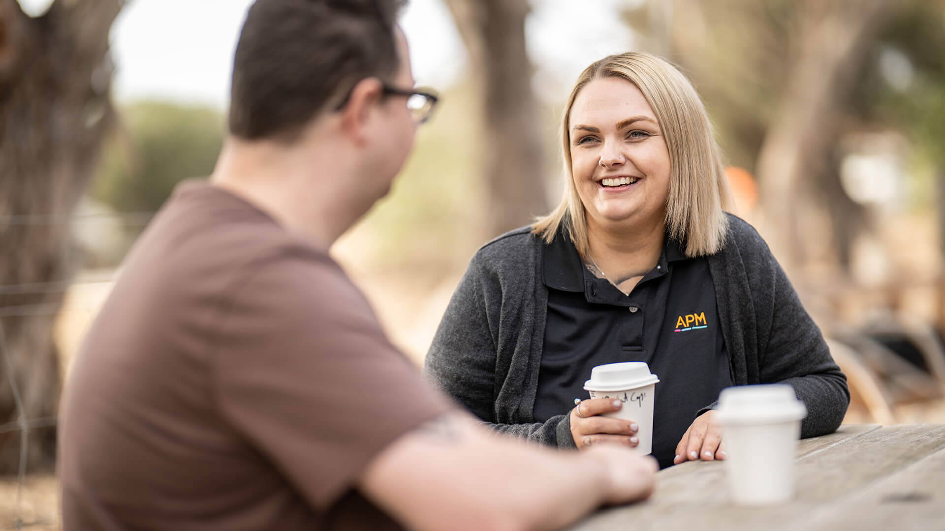 DES participant Sean sitting outside speaking to an APM consultant and having a coffee