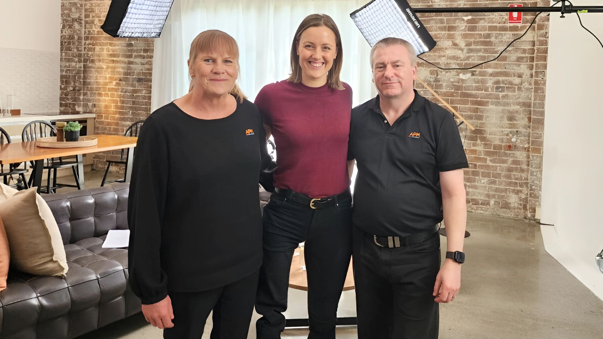 Ellie Cole between two APM team members in black polos