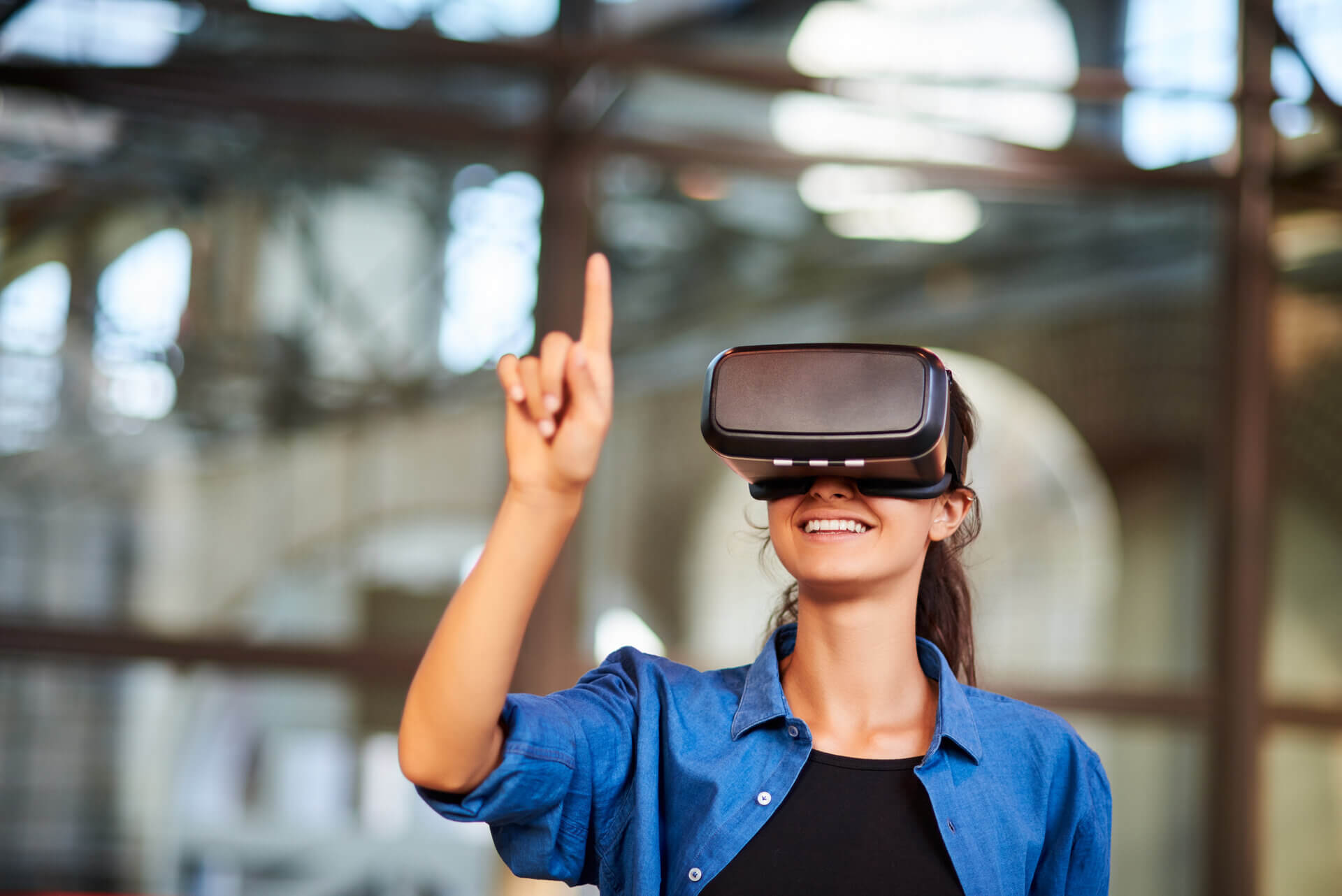 A woman wearing a VR headset and pointing up with right hand