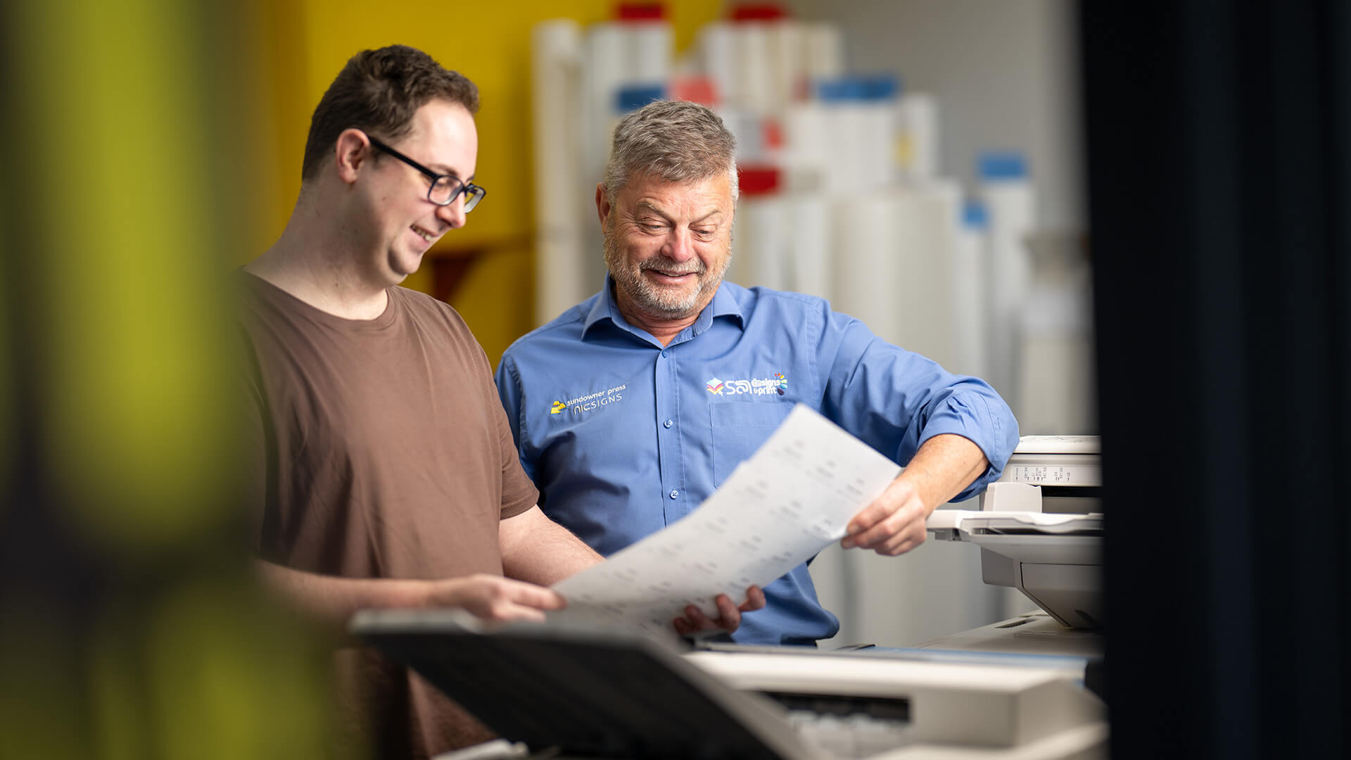 DES consultant with an employer look at a large item near a printer