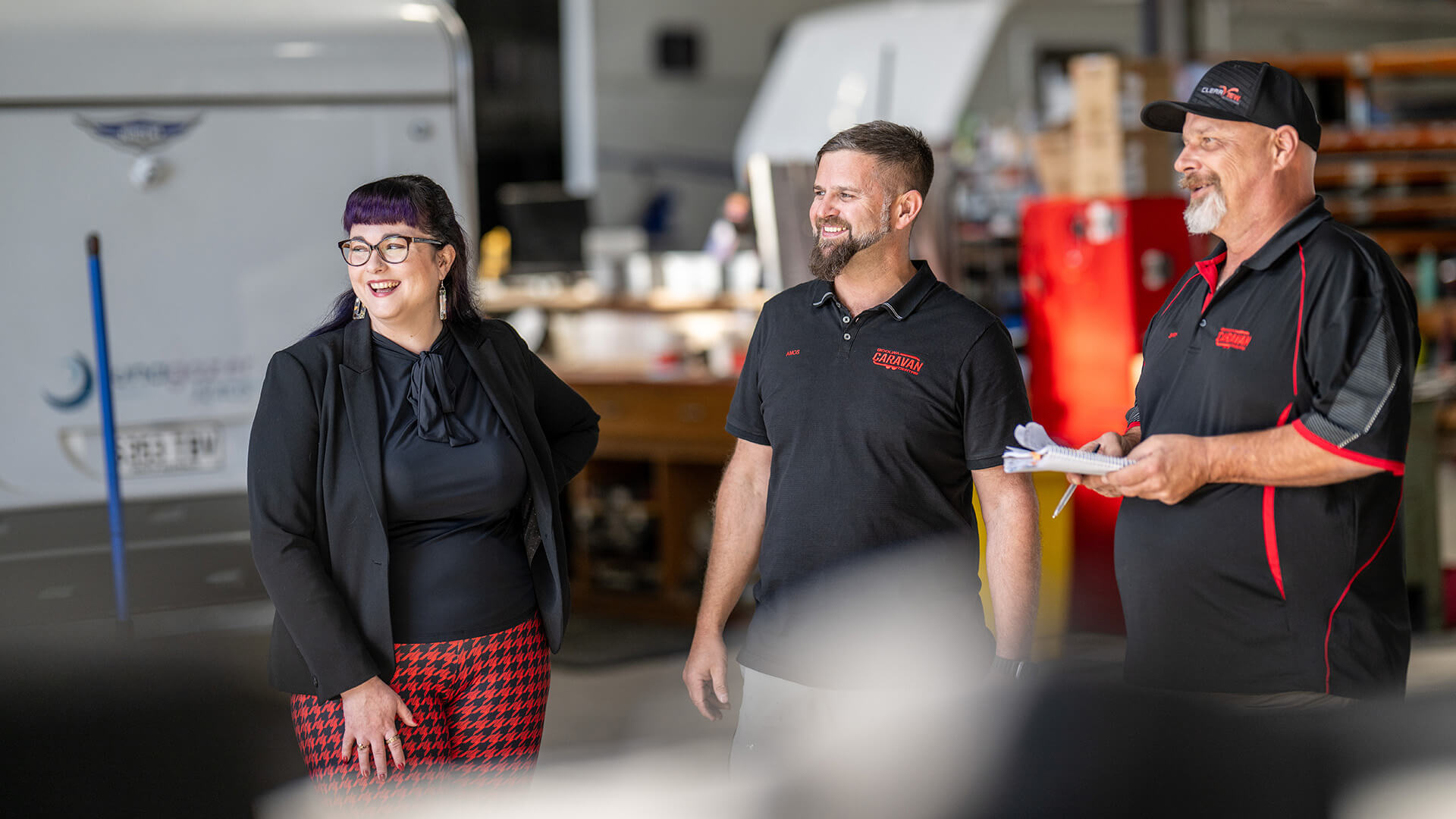 A woman and two men smiling in a warehouse discussing DES